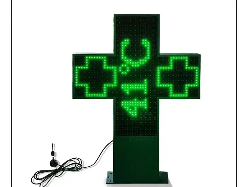 Cruz LED de farmacia verde sobre pie, mostrando la temperatura